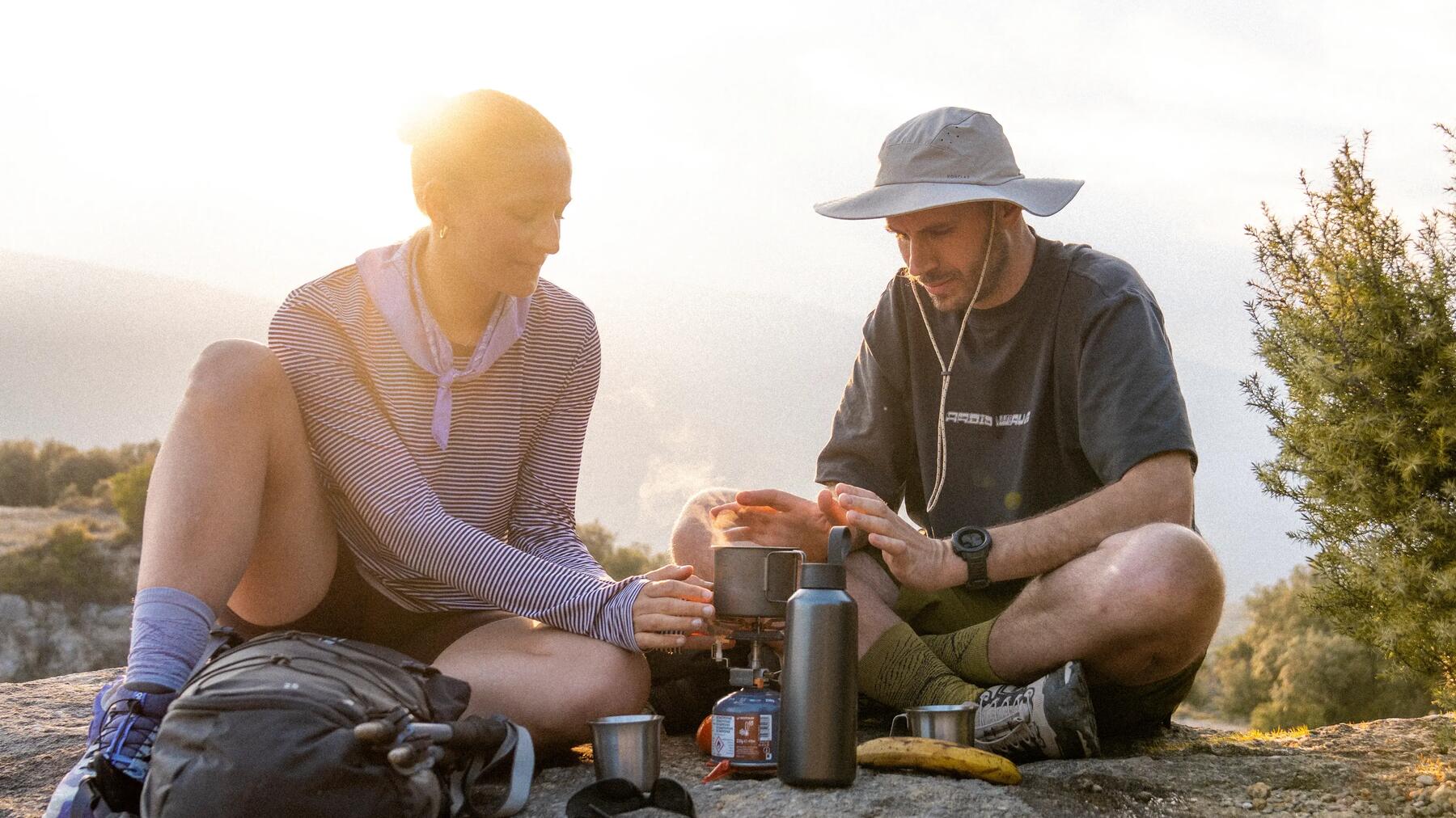 Ein Paar sitzt um die Camping Ausrüstung von Decathlon bei einem Picknick