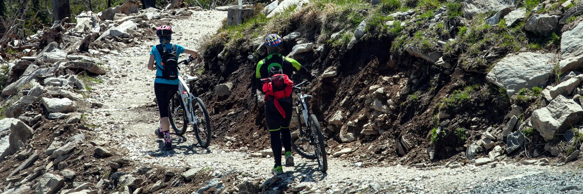 Rowerzyści idący z rowerami po Bike Park Czarna Góra