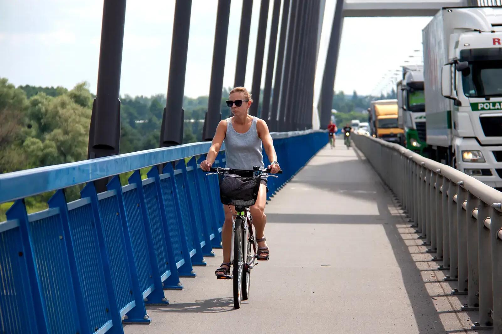 Kobieta jadąca na rowerze przez most