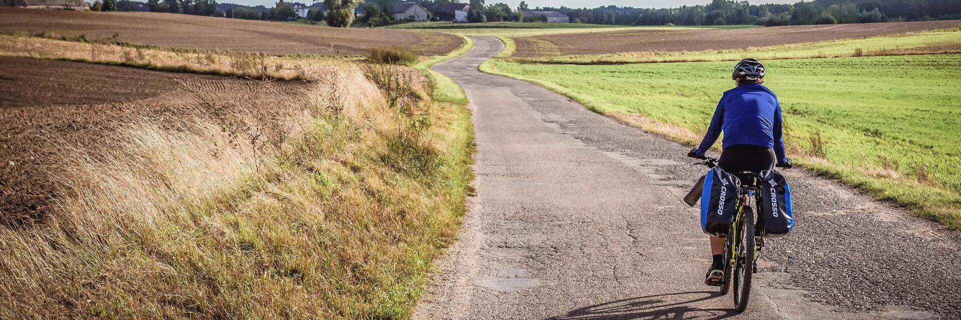 Rowerzysta w kasku jadący ścieżką rowerową na Mazurach