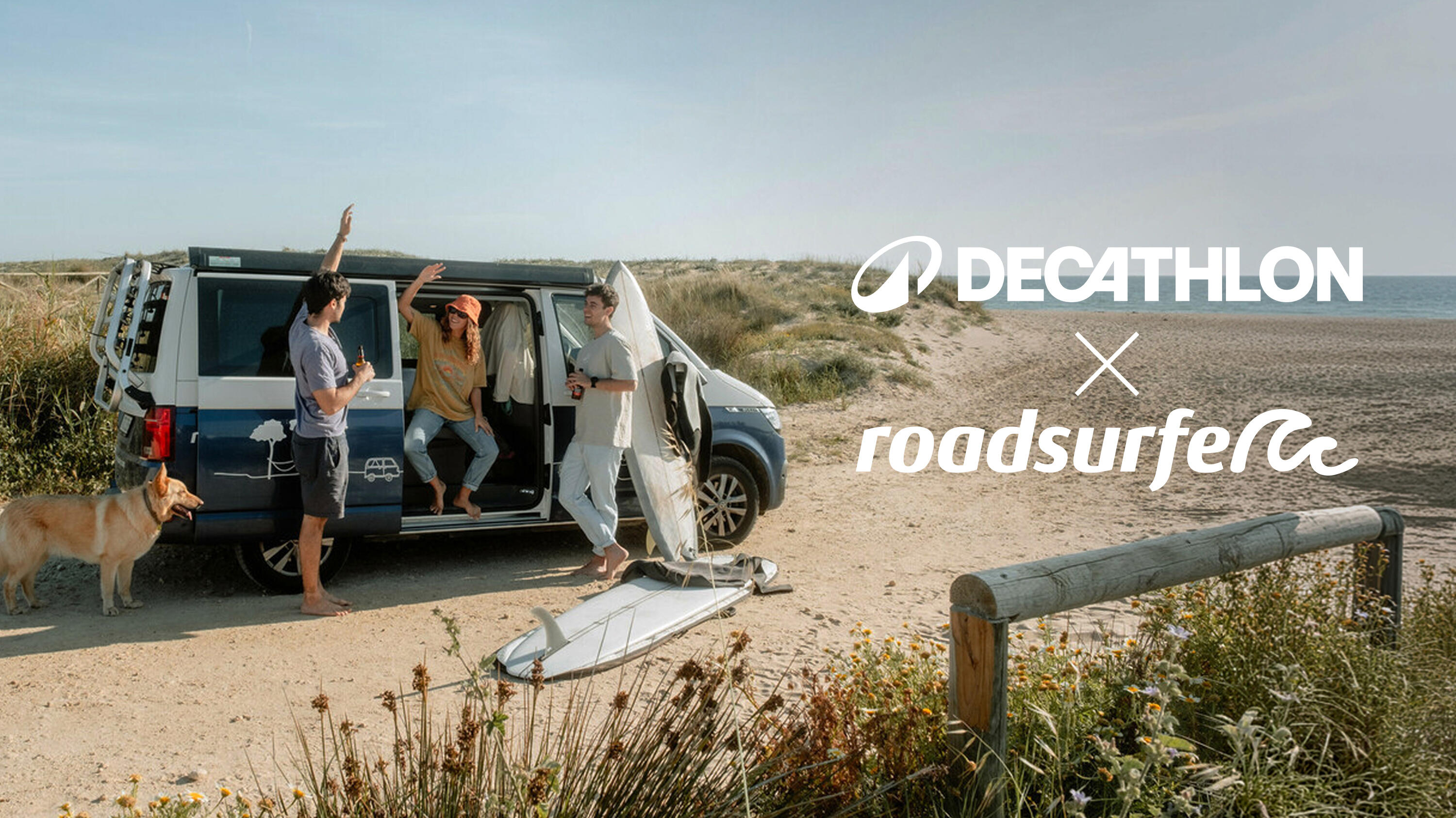 Strand-Szene mit drei Freunden, einem Hund und einem Roadsurfer-Campervan. Surfbretter lehnen am Van. Das Co-Branding-Logo „DECATHLON x roadsurfer“ ist oben rechts platziert.