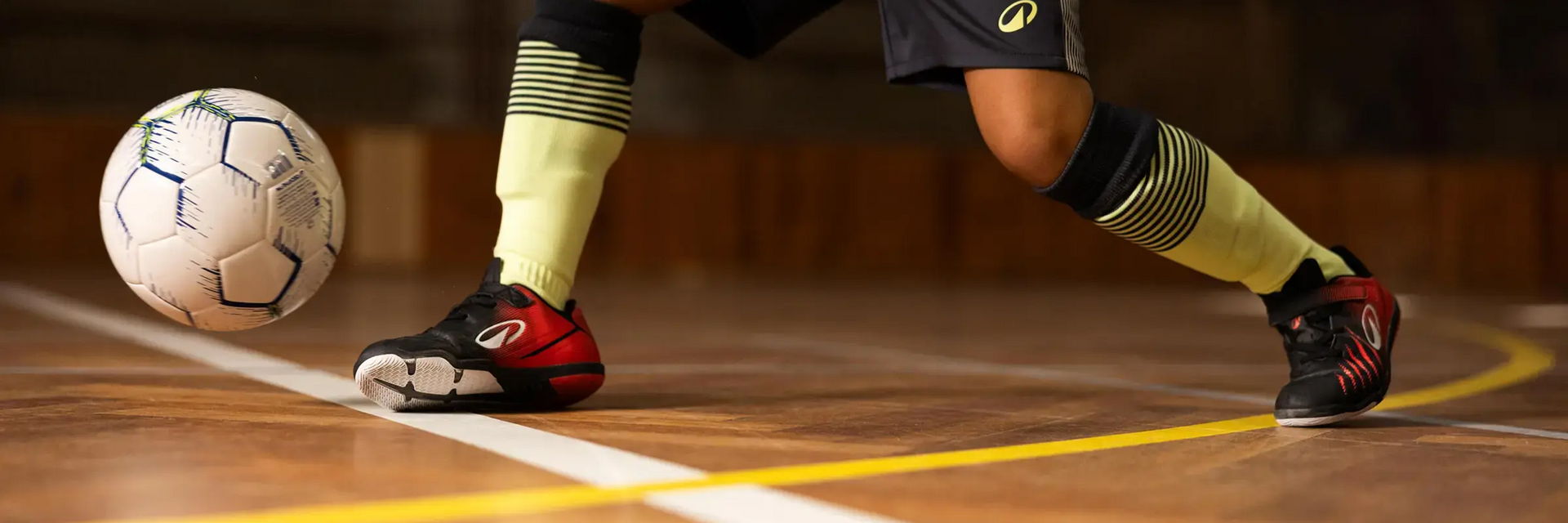 Osoba biegająca z piłką do futsalu po hali