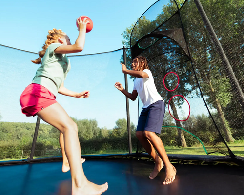 Dzieci skaczące na trampolinie z piłką