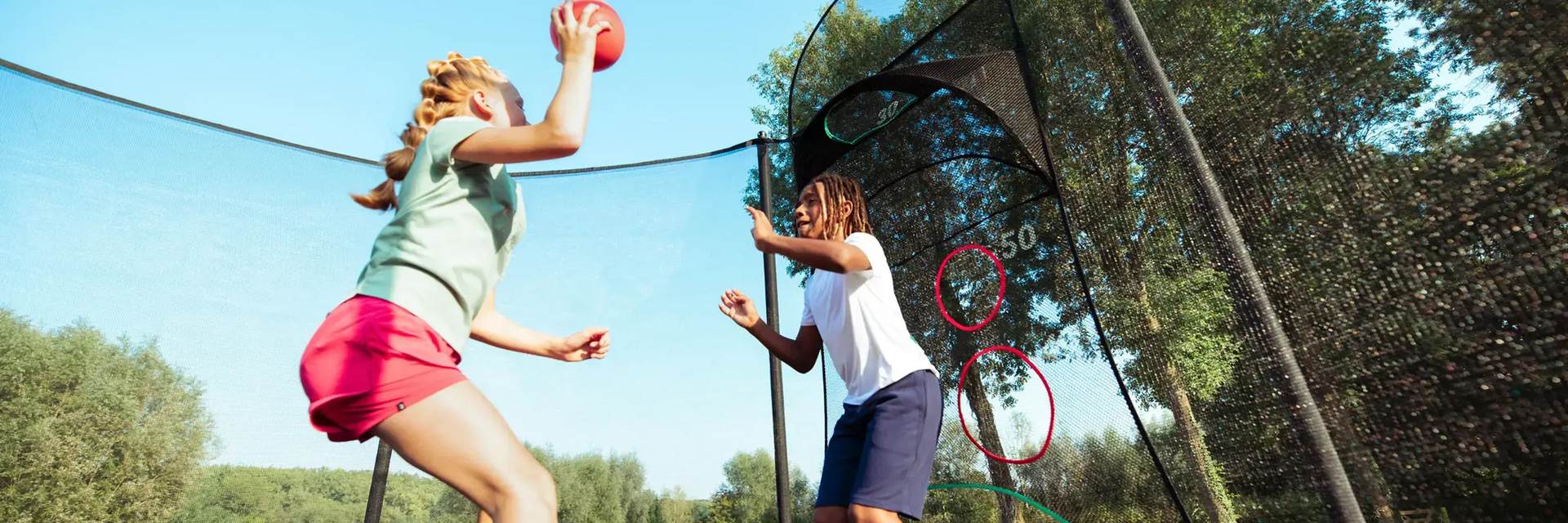 Dzieci skaczące na trampolinie z piłką