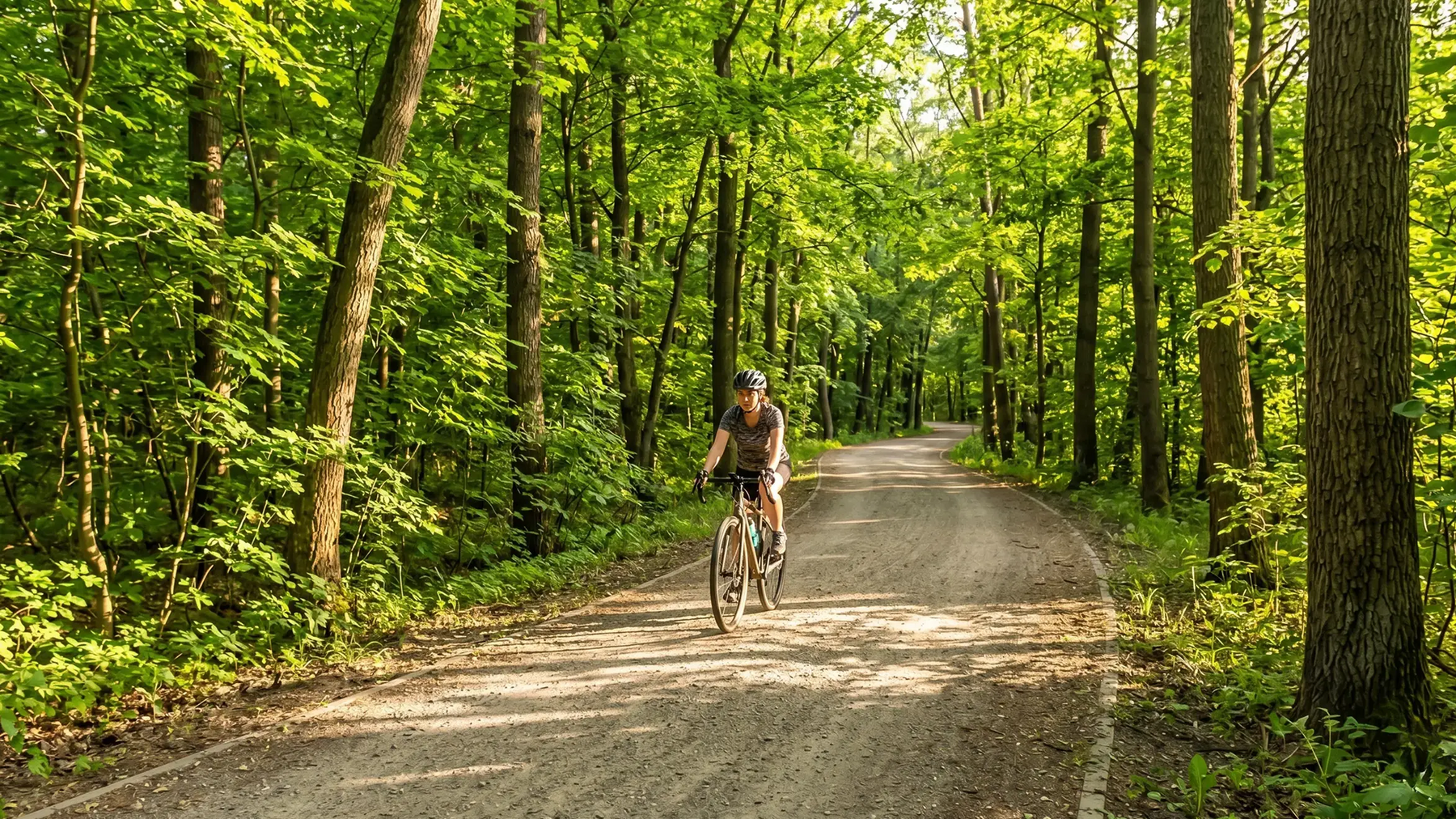 Rowerzystka w kasku jadąca po ścieżce rowerowej w lesie