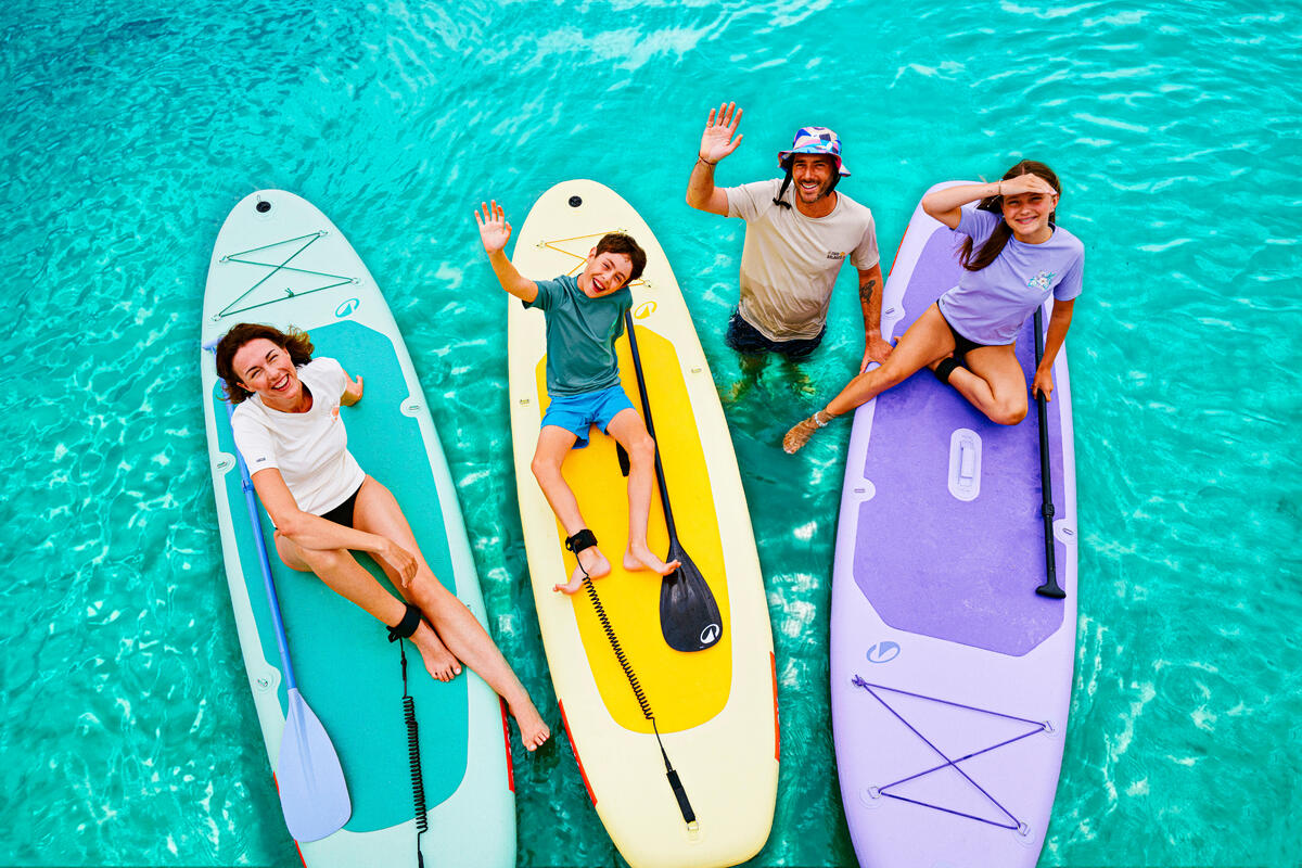 Četvoro ljudi na SUP daskama u tirkiznoj vodi, pogled odozgo.