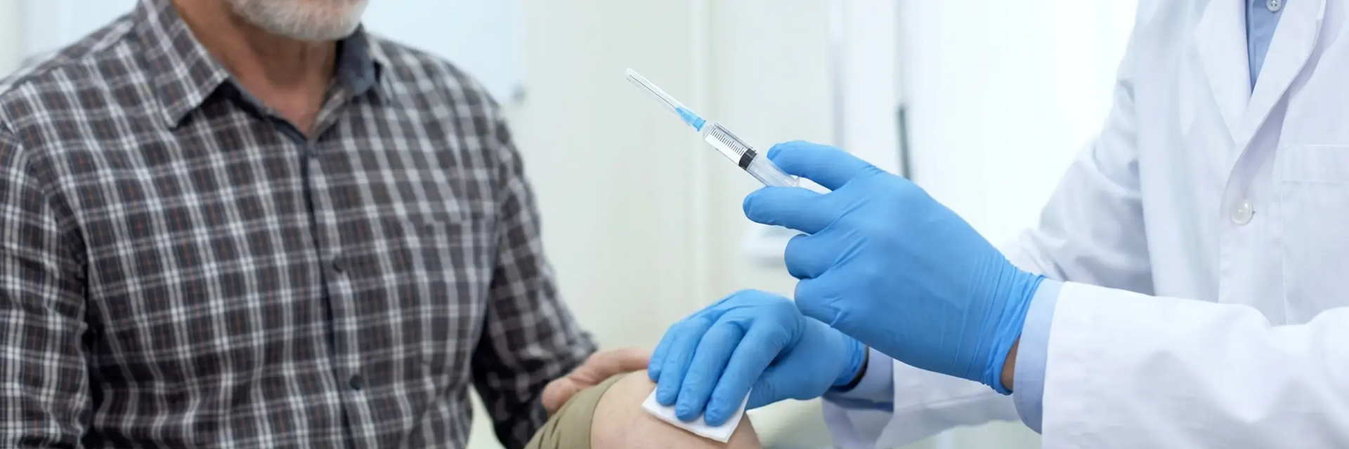 Lekarz trzymający w ręku zastrzyk blokada dezynfekujący drugą ręką staw kolanowy