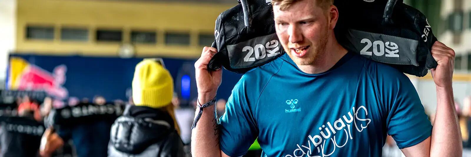 Mężczyzna niosący 20kg worek na barkach przygotowujący się do zawodów Hyrox