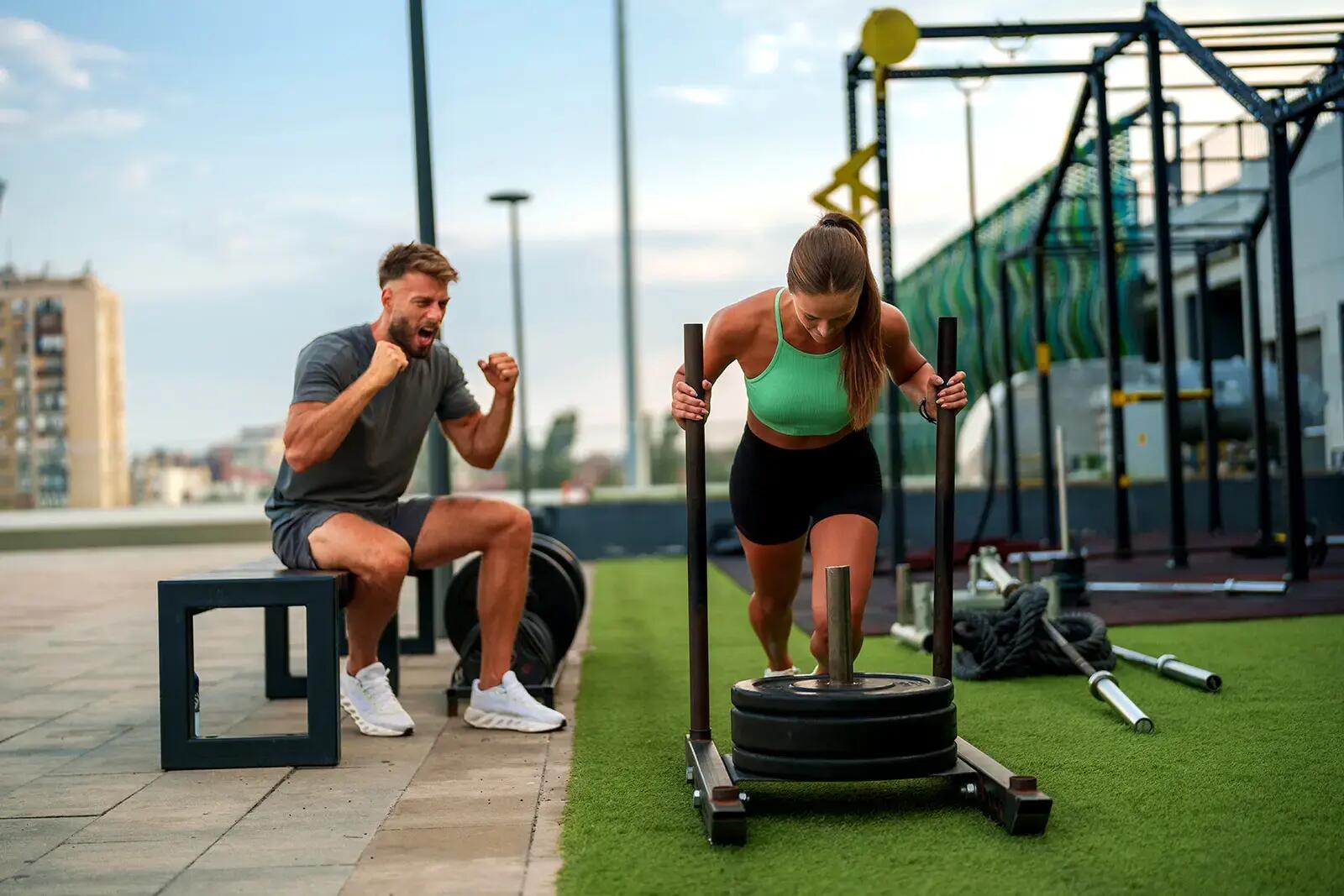Kobieta trenująca sled push obok trener