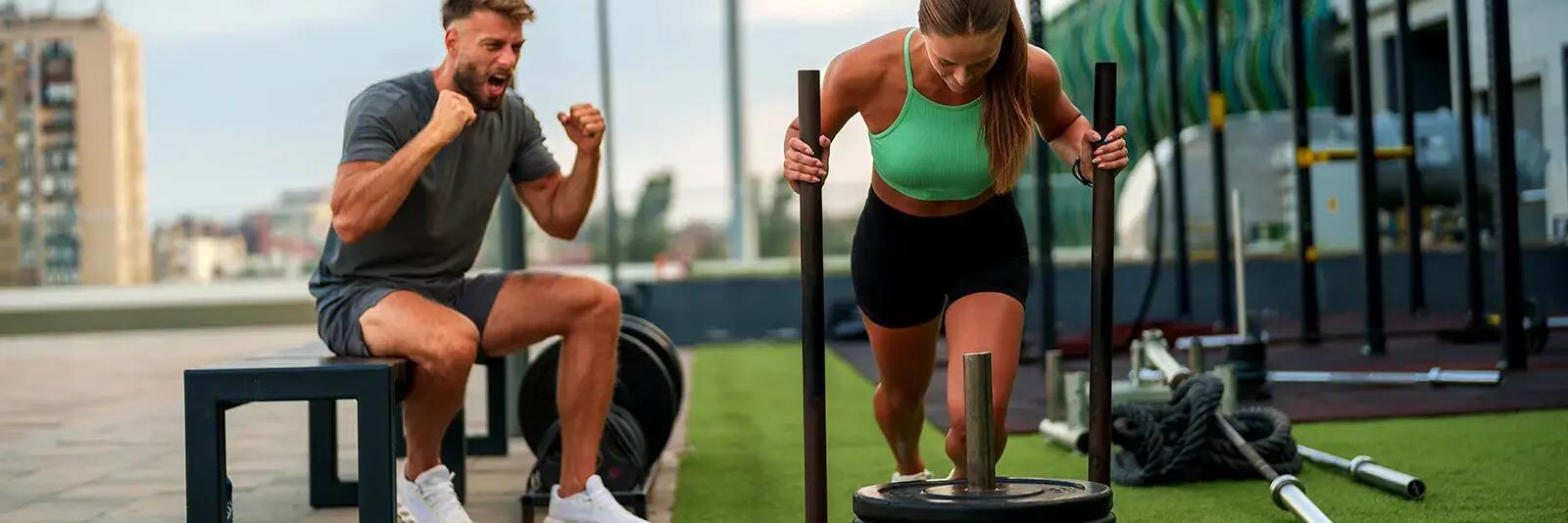 Kobieta trenująca sled push obok trener