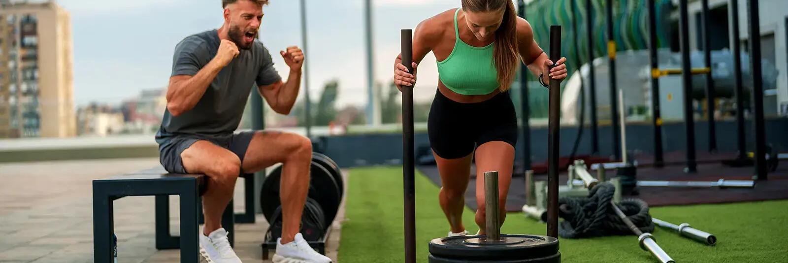 Kobieta trenująca sled push obok trener