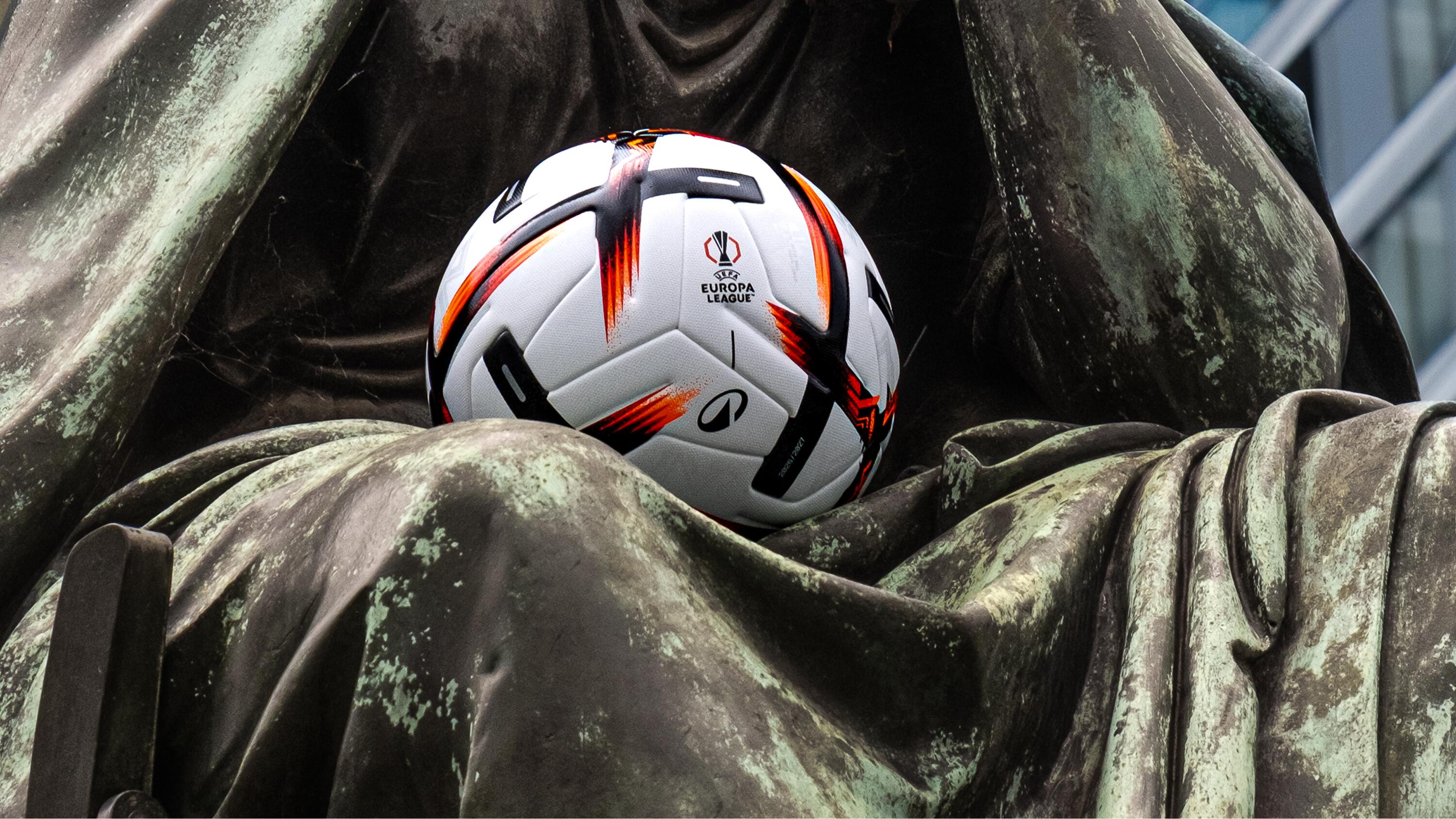 Ein offizieller UEFA Europa League Fußball der Saison 26/27 liegt auf einer Statue.