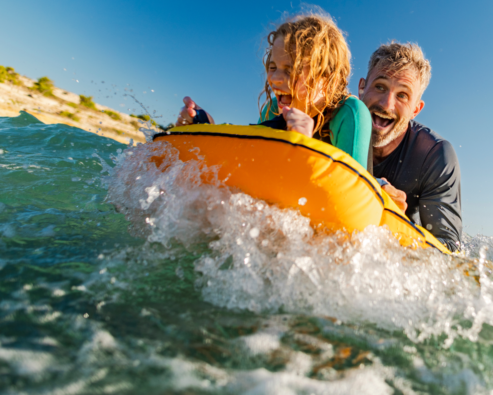 Zwei Menschen auf einer Luftmatratze im Meer, die Spaß haben