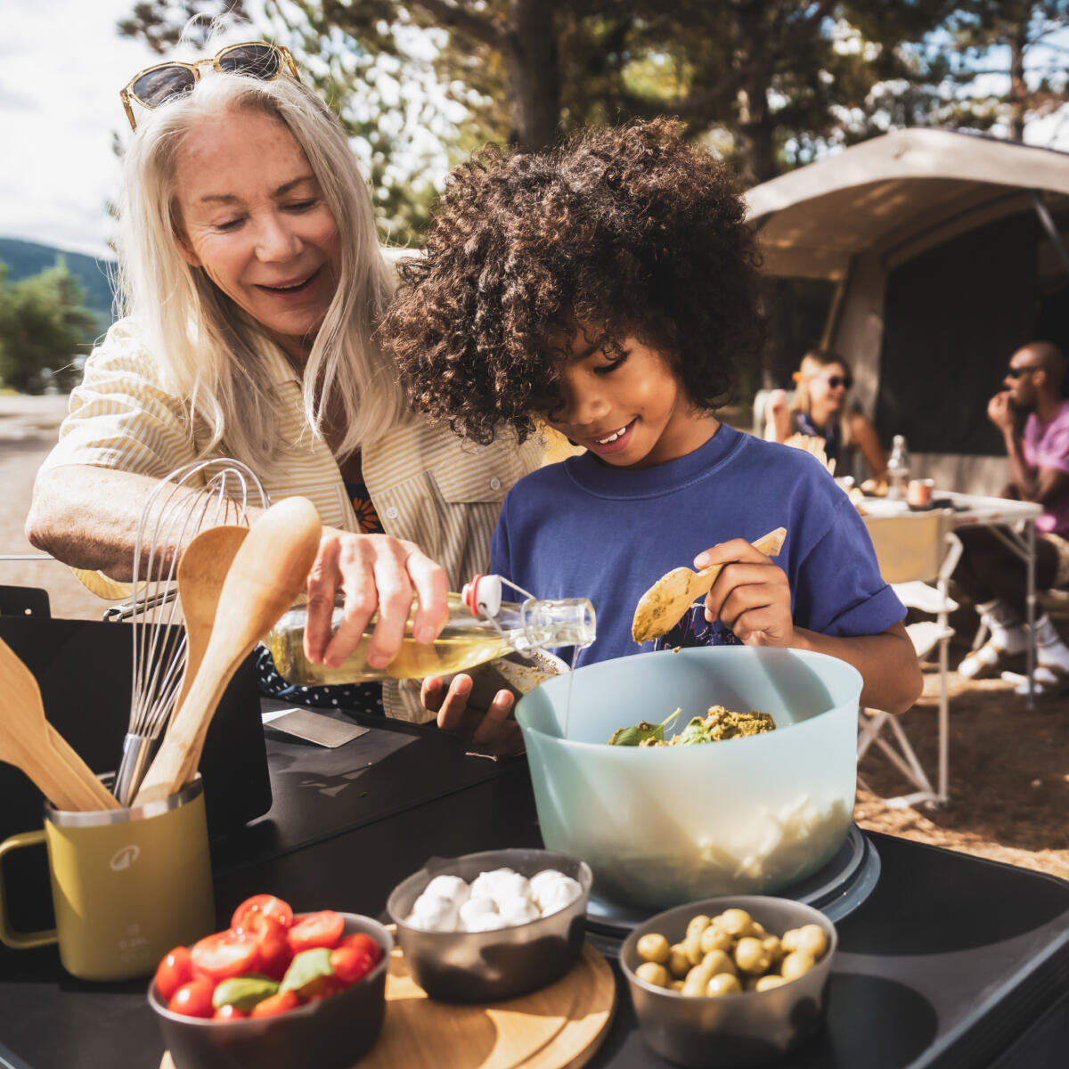 Klein meisje en haar oma maken een salade klaar op de camping