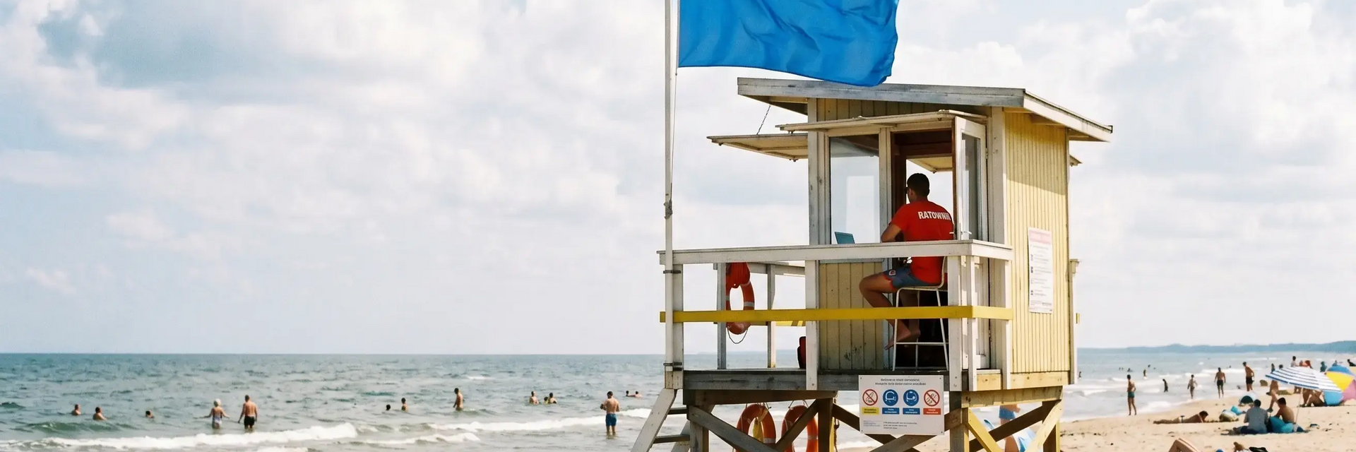 Niebieska flaga zamontowana przy domku ratowników na plaży