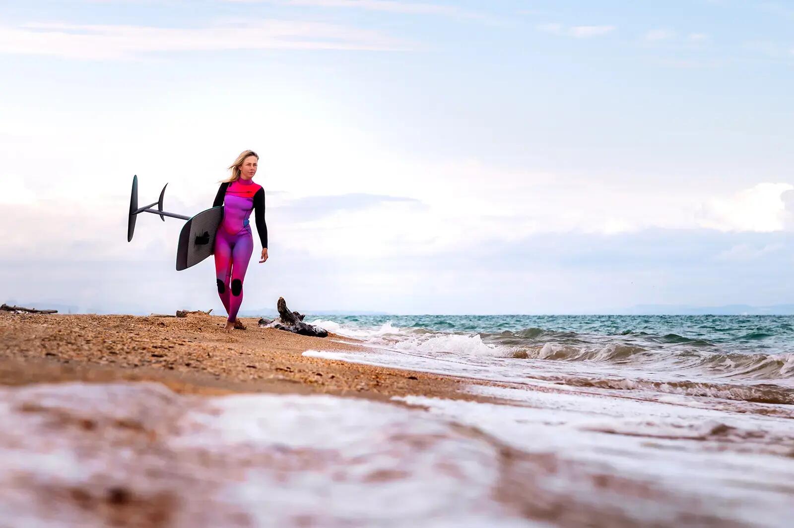 Kobieta idąca plażą z hydrofoilem
