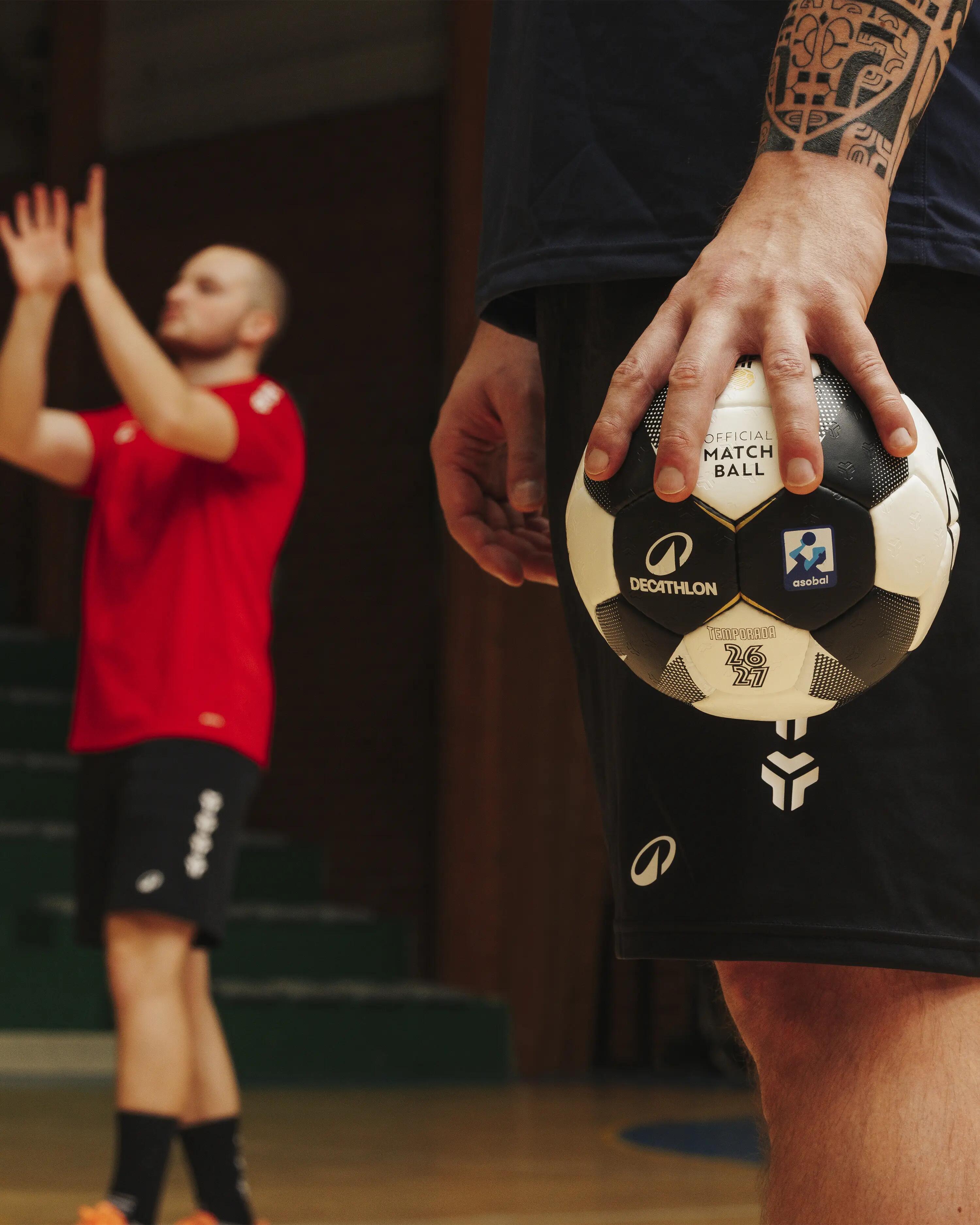 Ein Decathlon Handball im Vordergrund, im Hintergrund ein Handballer, der einen Ball fngt