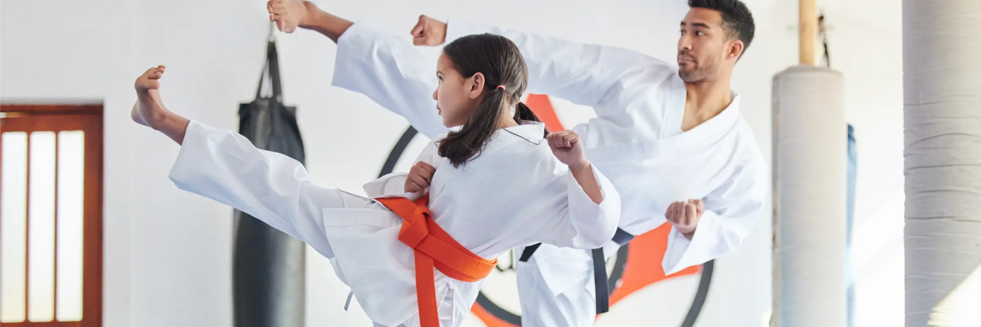 Dziewczynka z trenerem w karategach trenująca kopnięcia w karate
