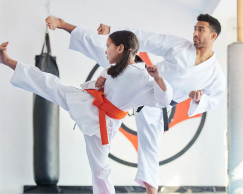Dziewczynka z trenerem w karategach trenująca kopnięcia w karate