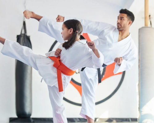 Dziewczynka z trenerem w karategach trenująca karate wydająca okrzyk kiai