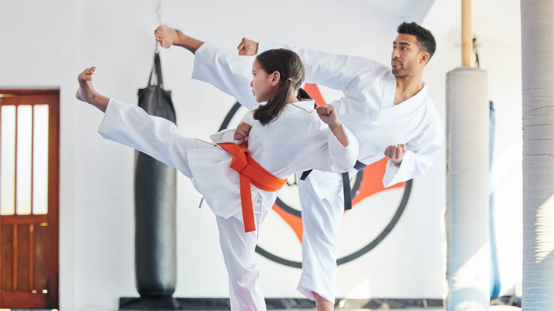 Mężczyzna trenujący z dziewczynką karate na sali