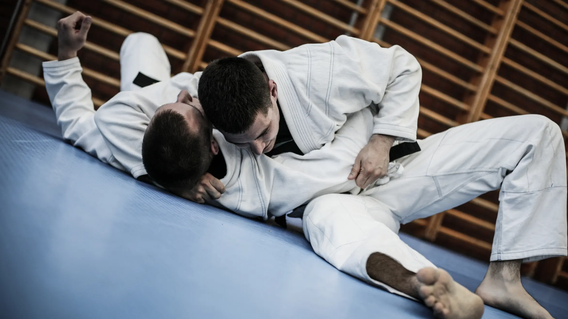 Mężczyźni trenujący na ziemi kata gatame w judo