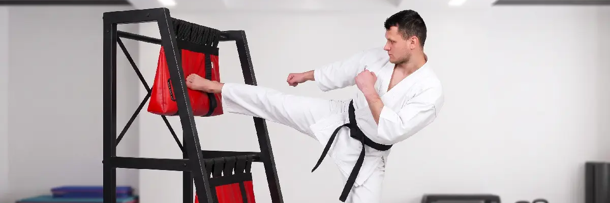 Mężczyzna uderzający nogą w worek treningowy makiwara do treningu karate