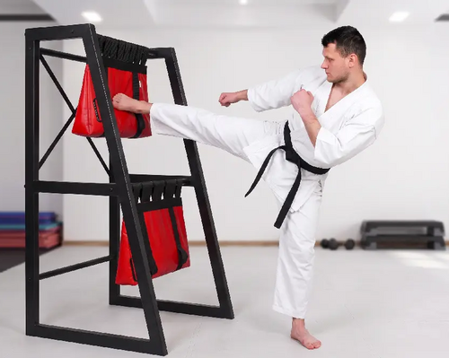 Mężczyzna uderzający nogą w worek treningowy makiwara do treningu karate