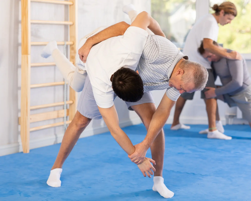 Mężczyźni trenujący soto makikomi w judo