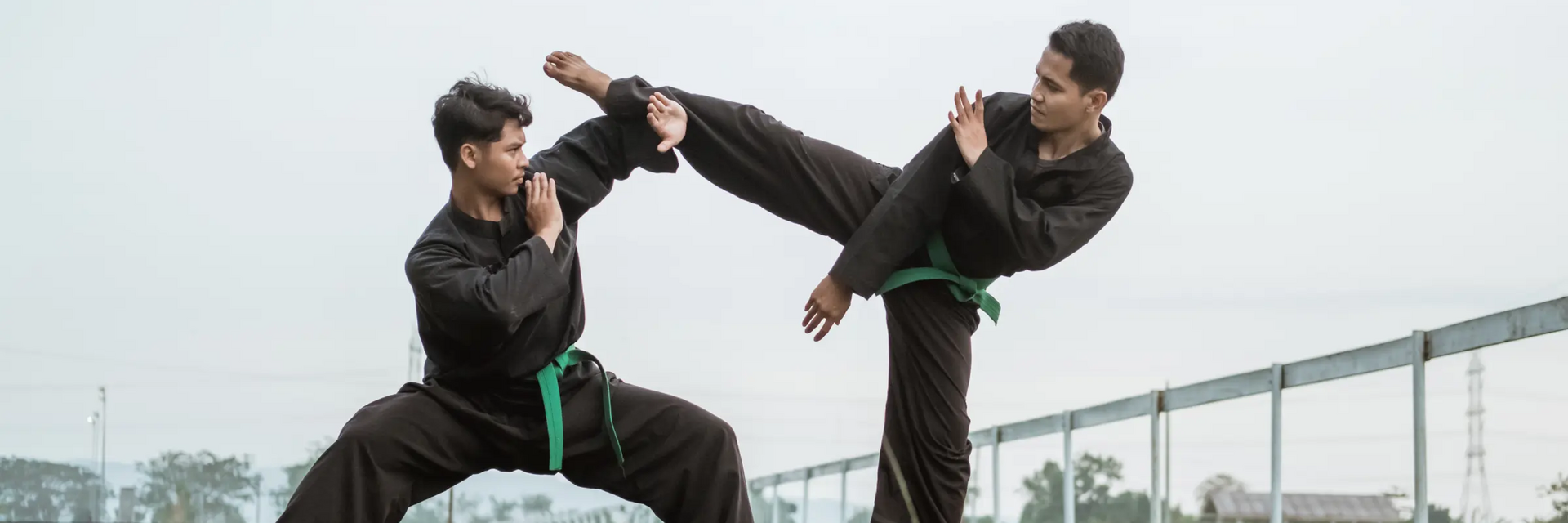 Dwóch nastolatków w karategach trenujący pencak silat na trawie