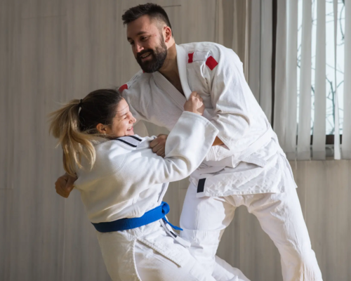 Kobieta z trenerem trenująca yoko otoshi w judogach