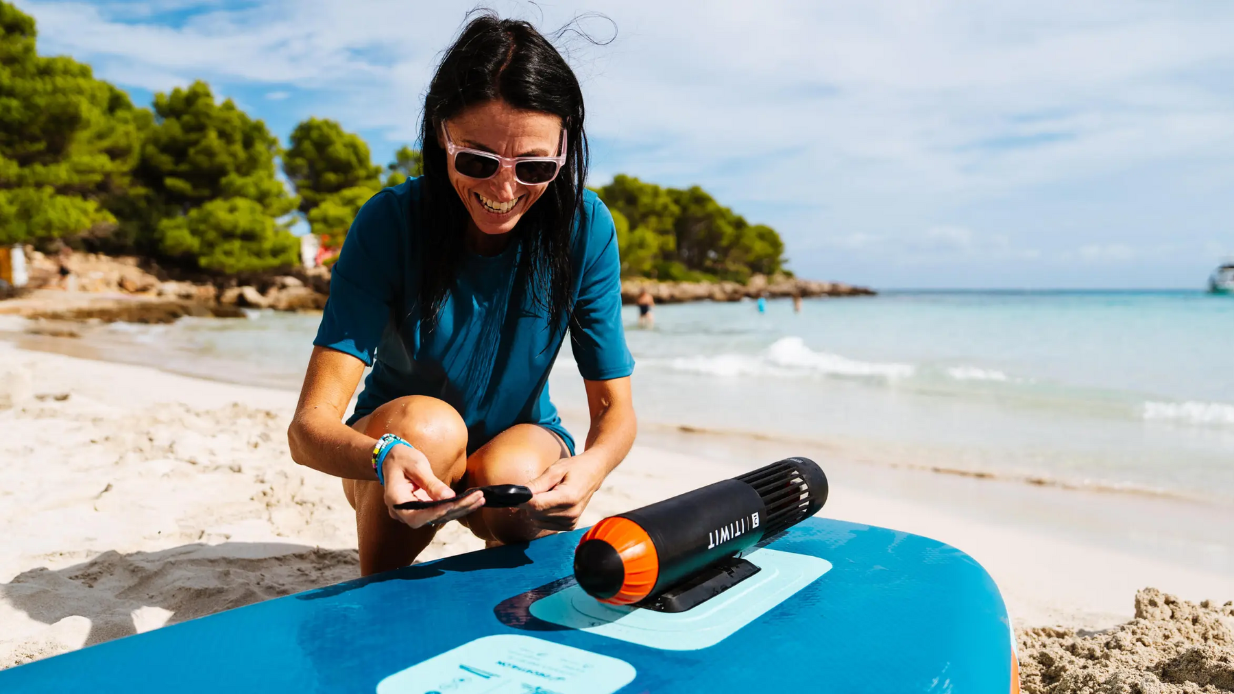 Kobieta montująca silnik elektryczny do kajka na plaży