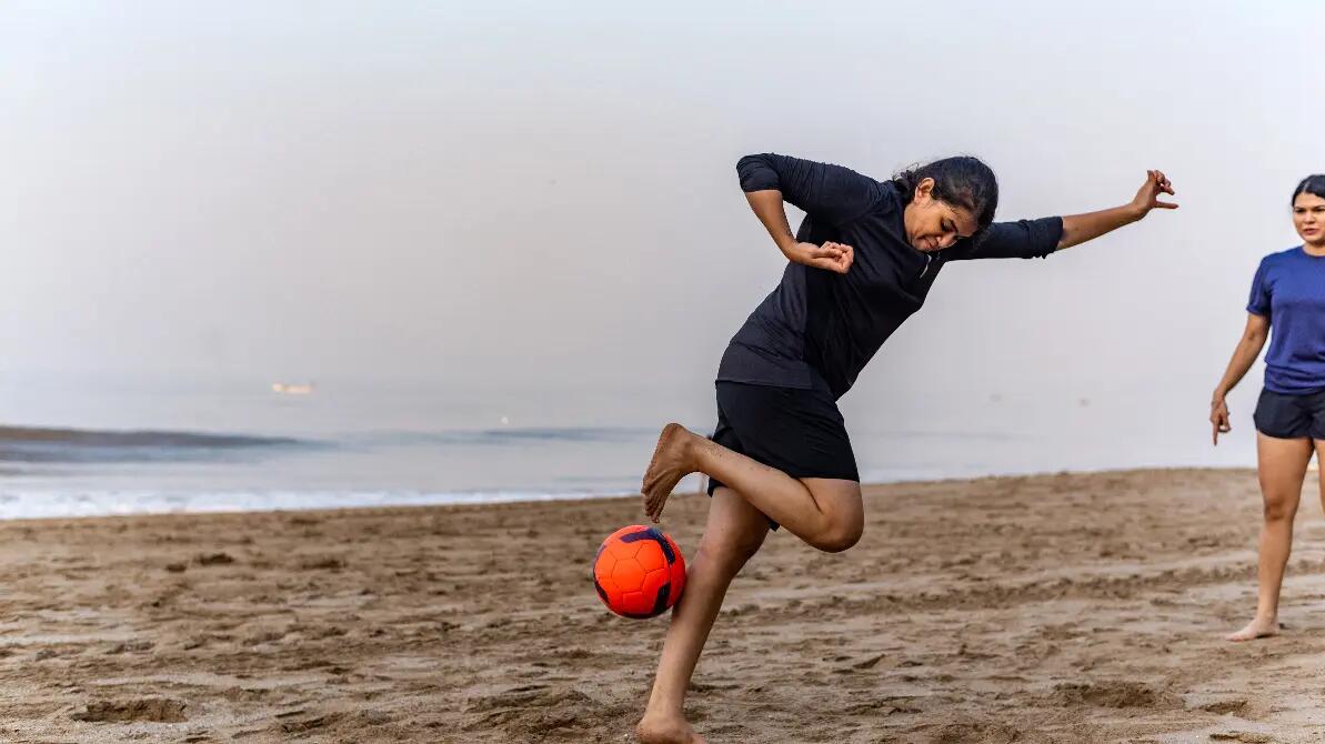 Dziewczyna na plaży próbująca wykonać rainbow flick