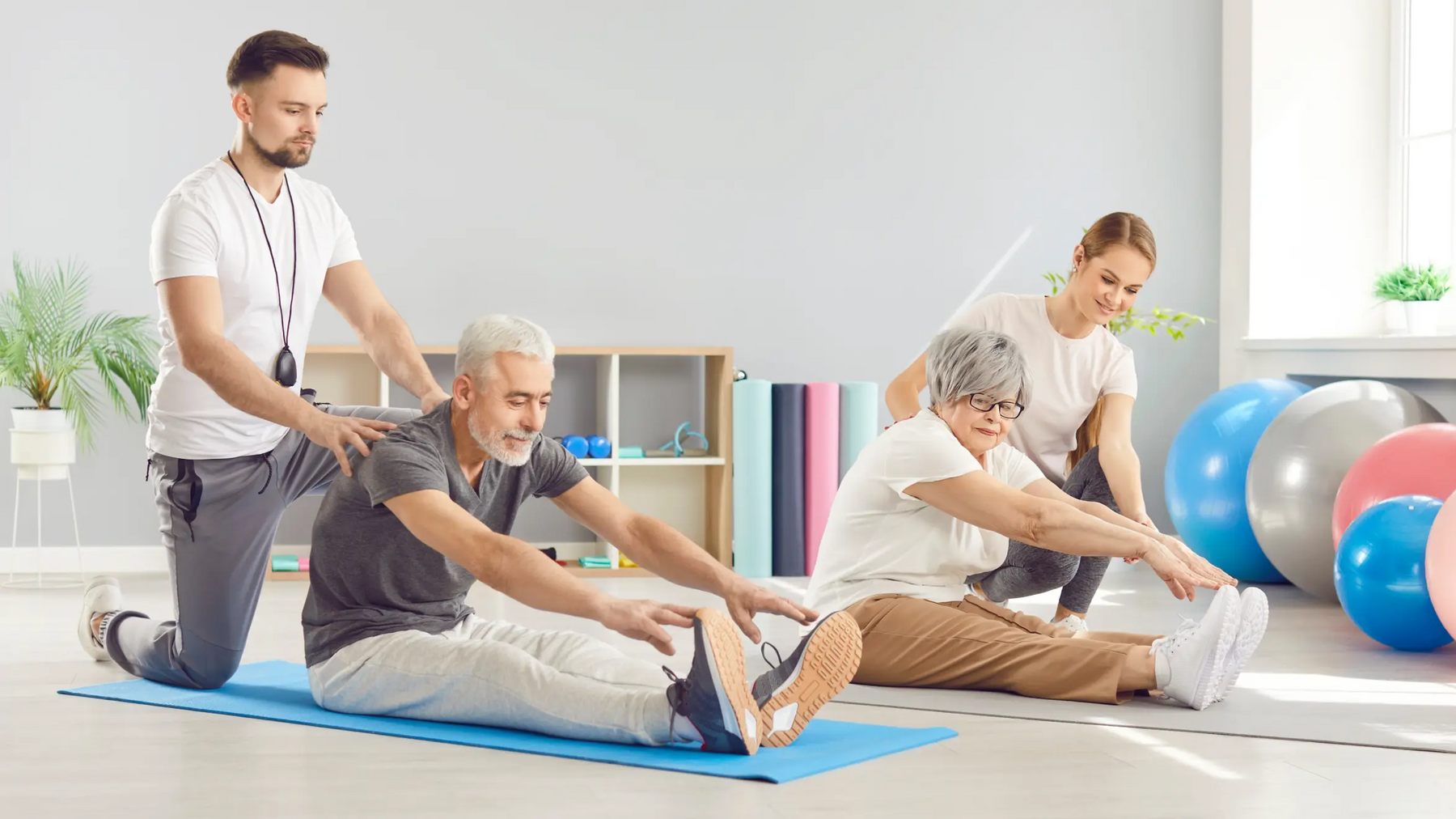 Seniorzy ćwiczący z rehabilitantami na matach