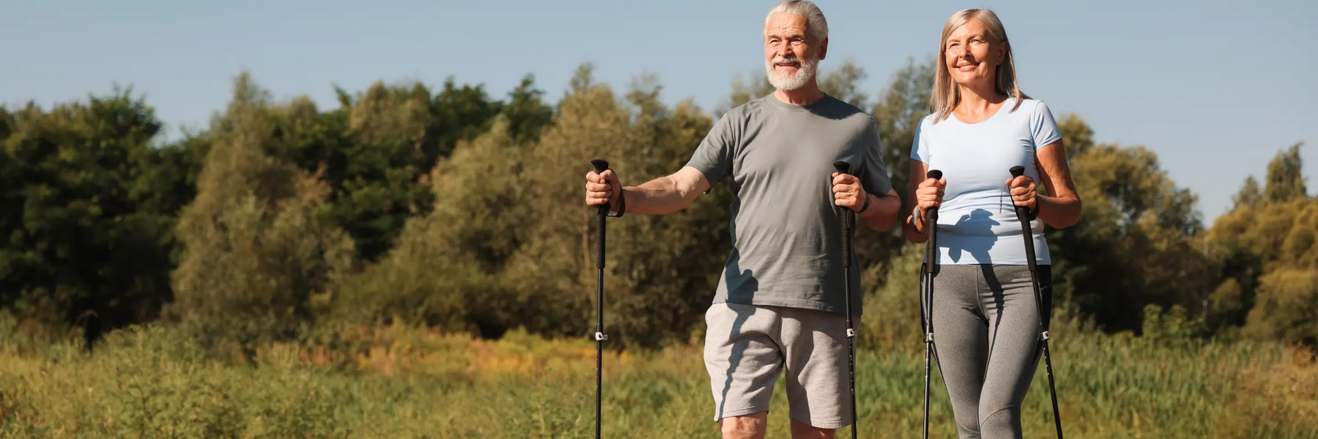 Seniorzy uprawiający nordic walking w terenie