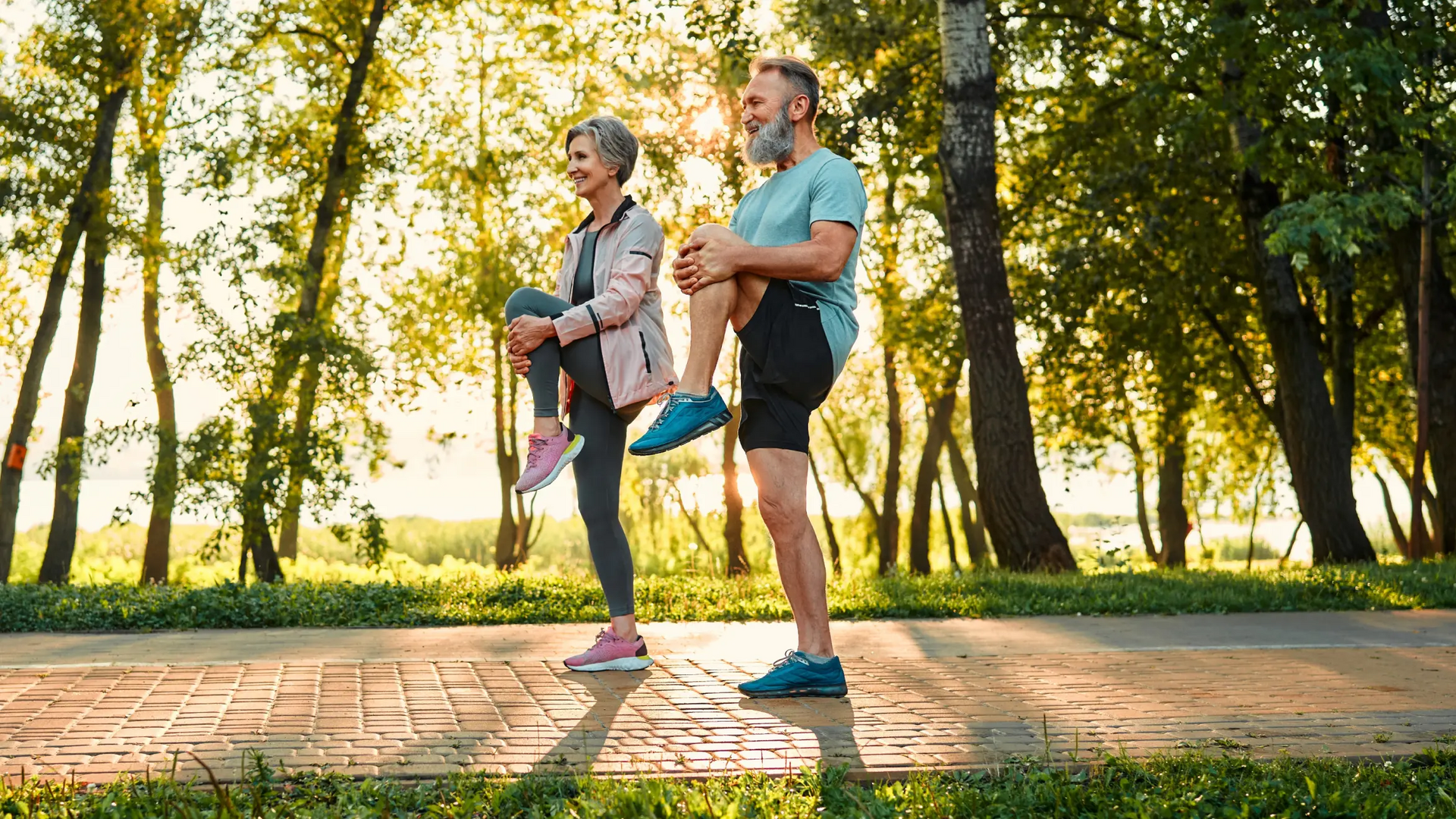 Para seniorów stojąca na jednej nodze na chodniku w parku