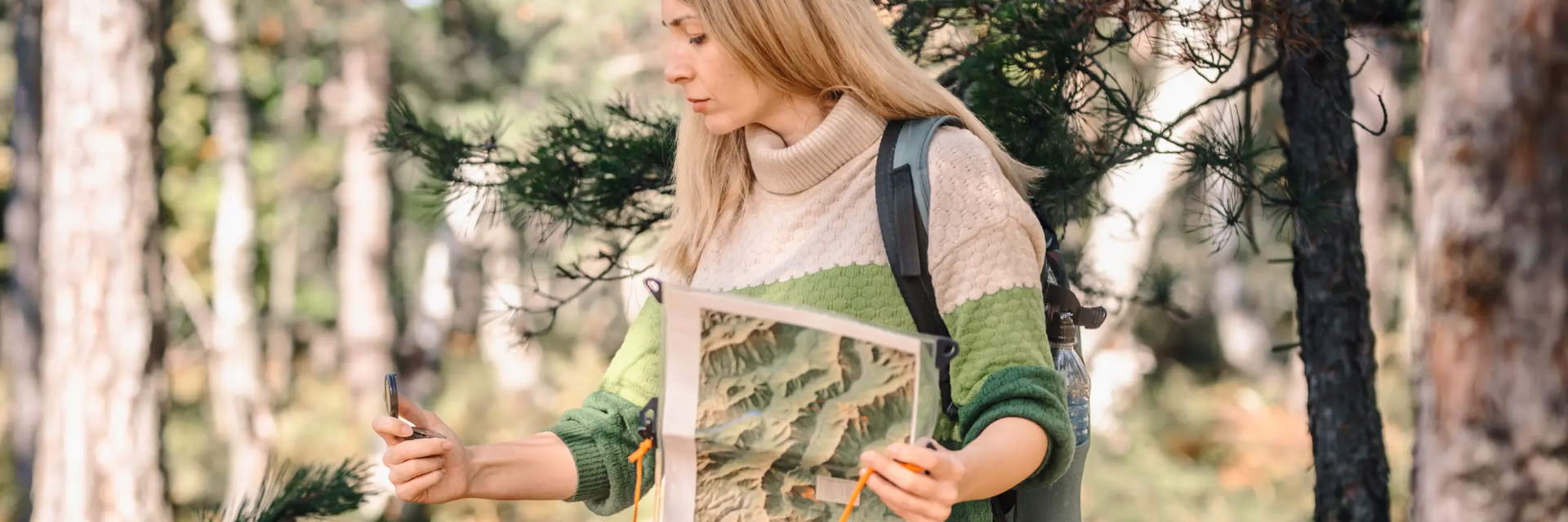 Kobieta chodząca z mapą i kompasem po lesie grająca w questing