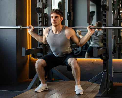 Mężczyzna ćwiczący przysiad z pinów pin squat na siłowni