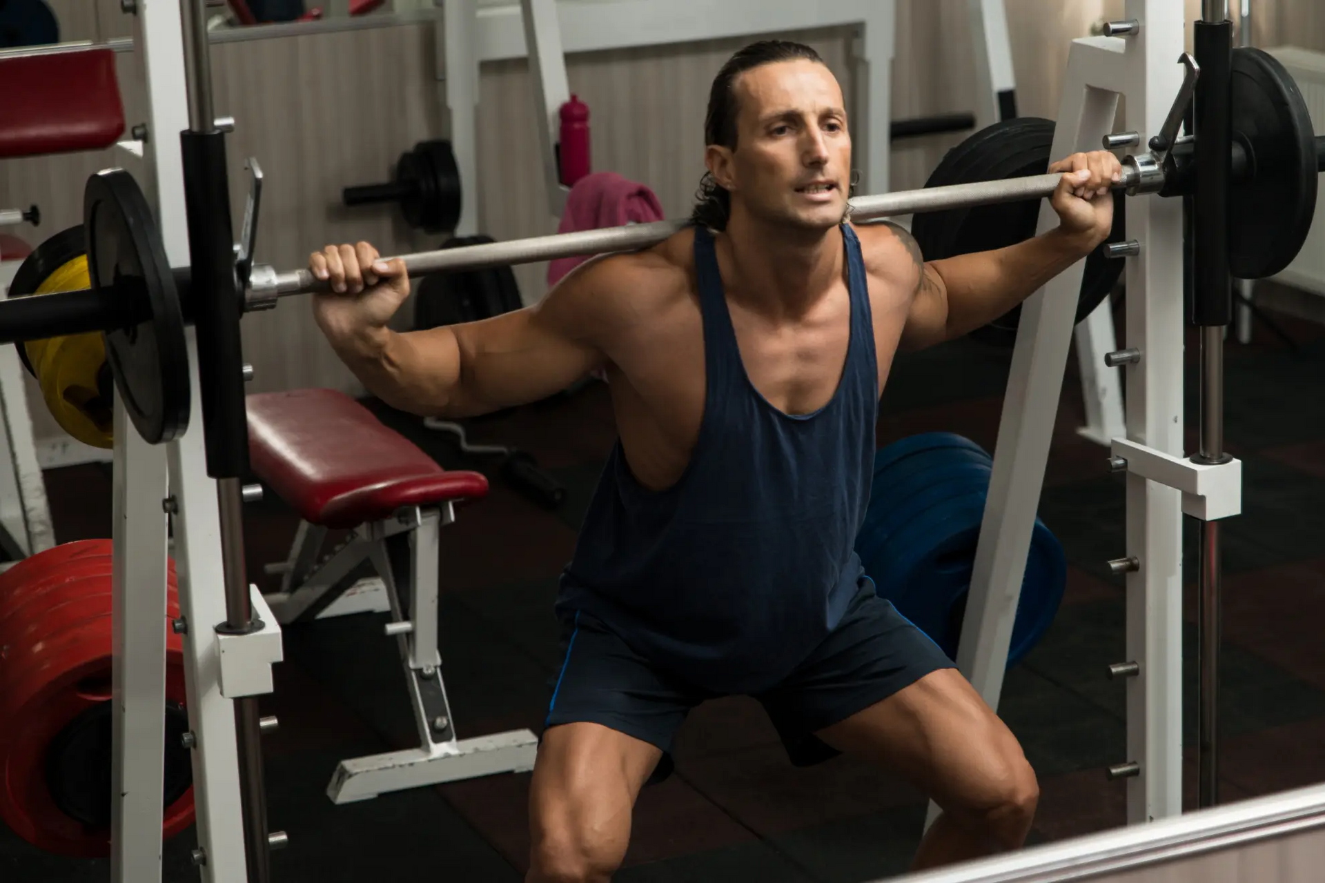 Mężczyzna ćwiczący przysiad z pinów pin squat na siłowni