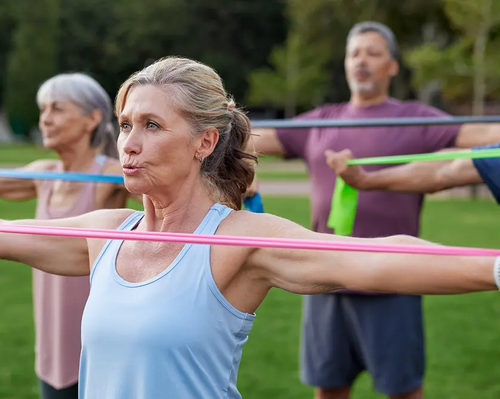 Seniorzy ćwiczący z gumą ćwiczenia na pelikany na stojąco