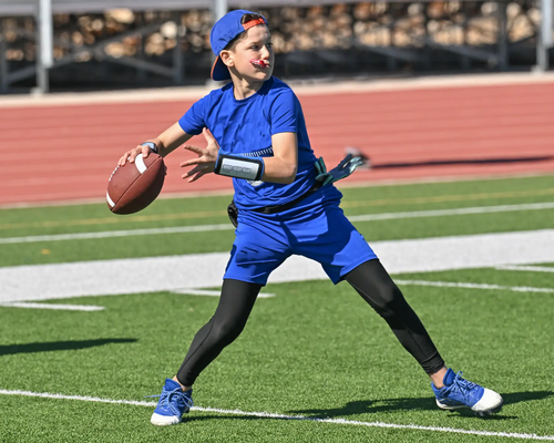Chłopiec z piłką do rugby w ręku grający we flag football