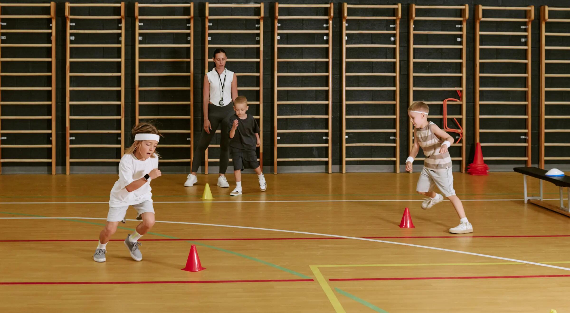 Dzieci trenujące bieg po kopercie na sali sportowej