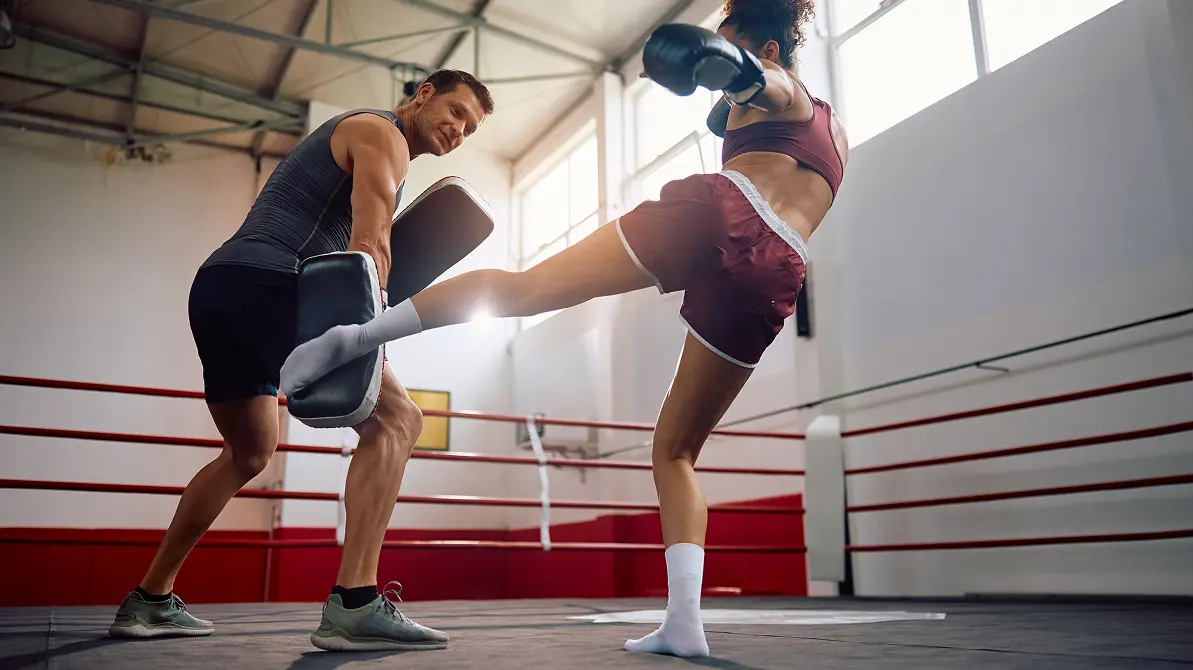 Kobieta i mężczyzna trenujący low kick w ringu