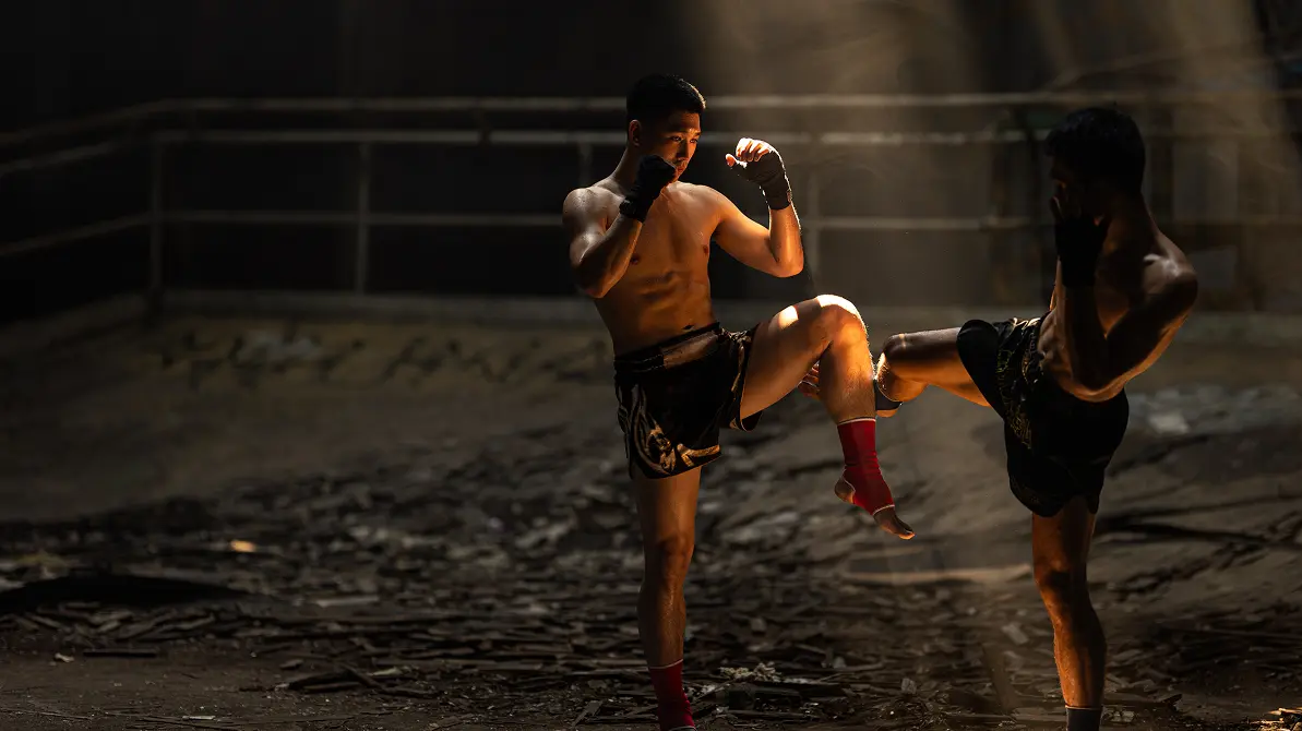 Dwóch mężczyzn w rękawicach trenujący kopnięcia w mma