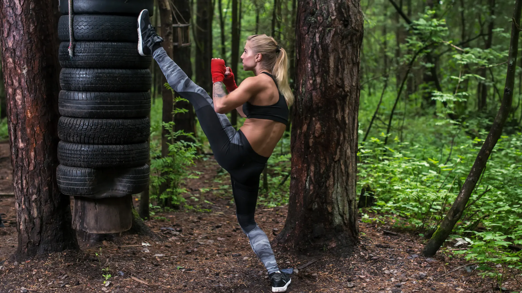 Kobieta trenująca axe kick w lesie