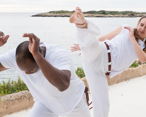 Kobieta z mężczyzną trenujący capoeira kick