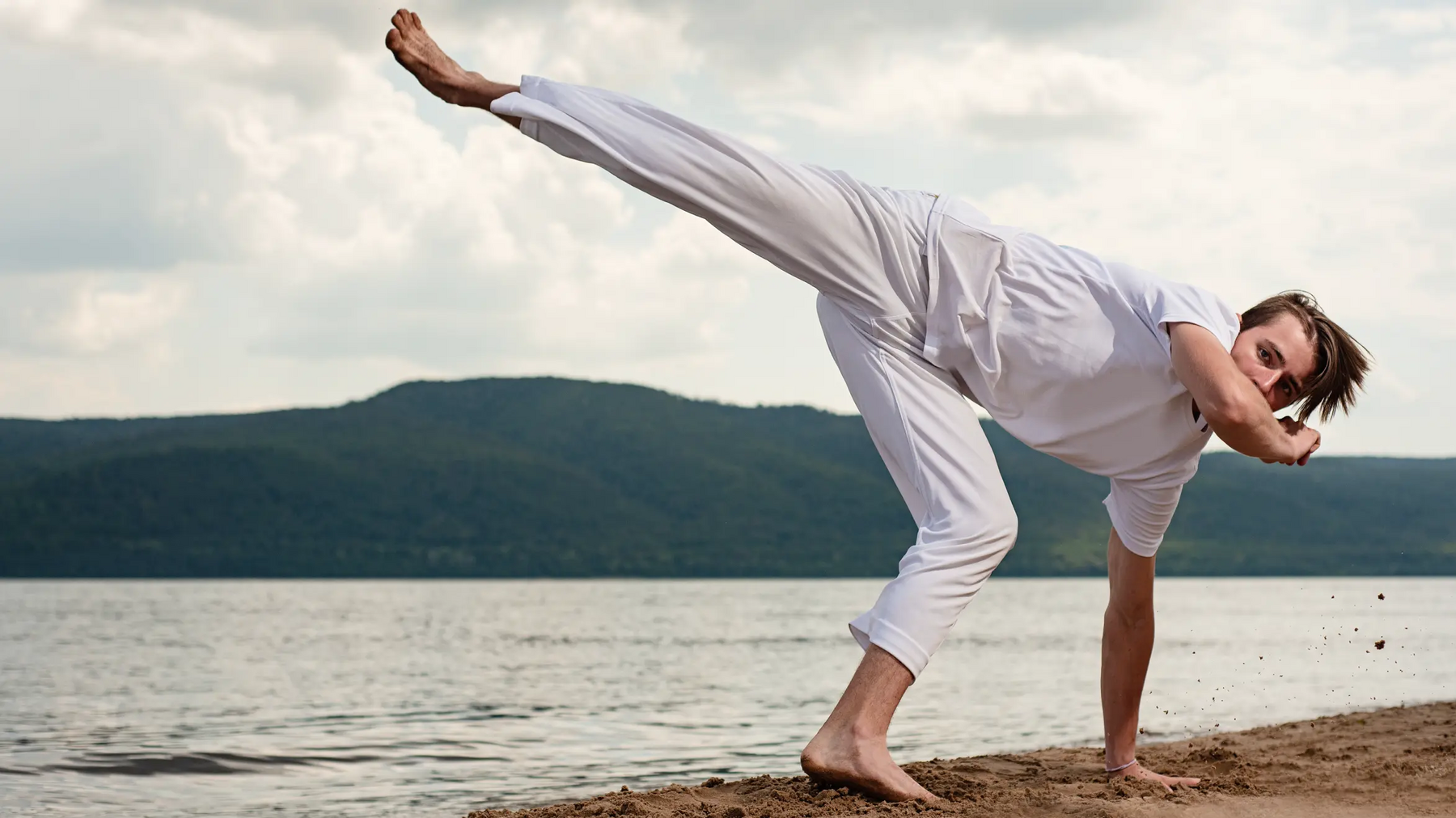 Mężczyzna trenujący capoeira kick na plaży