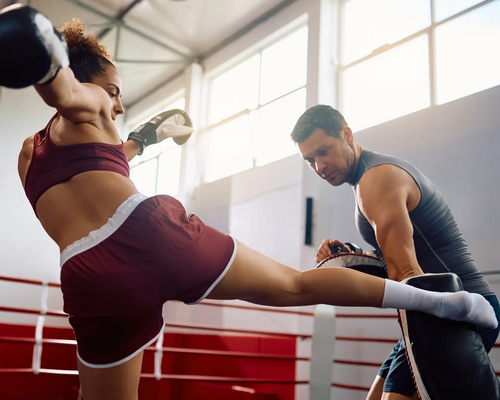 Kobieta w rękawicach trenująca z mężczyzną middle kick