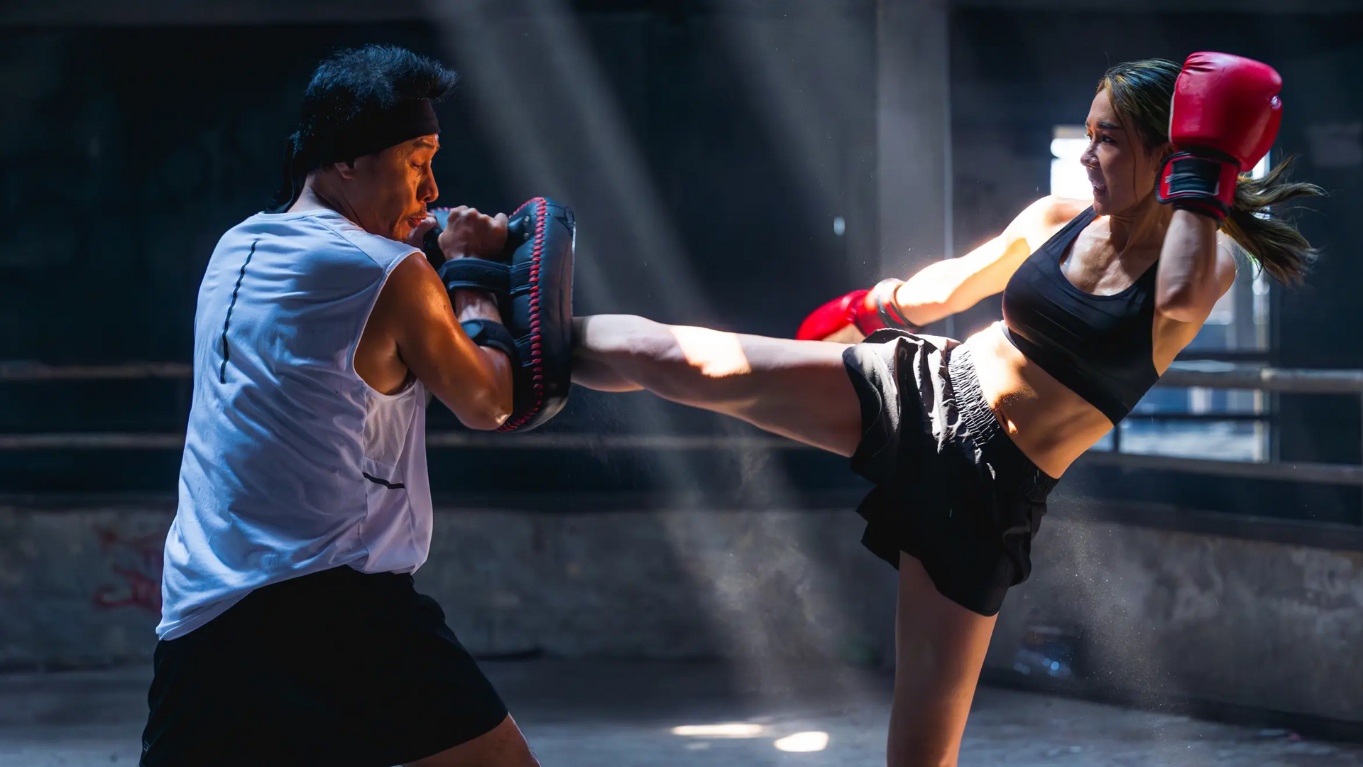 Kobieta w rękawicach trenująca z mężczyzną middle kick