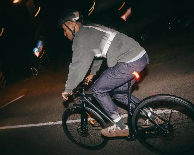 A men is cycling through the night with high visibility clothes on